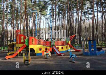Toboganes y columpios para niños en el parque infantil en el parque de la ciudad Foto de stock