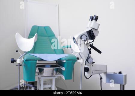 Moderno colposcopio binocular y silla ginecológica en clínica Foto de stock
