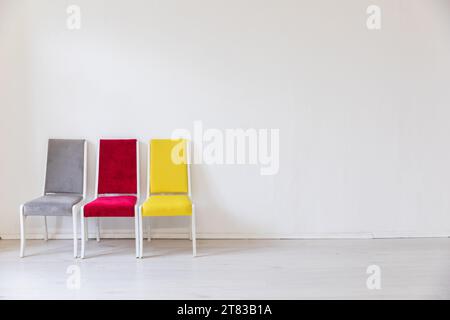 sillas grises rojas amarillas sobre fondo blanco interior Foto de stock
