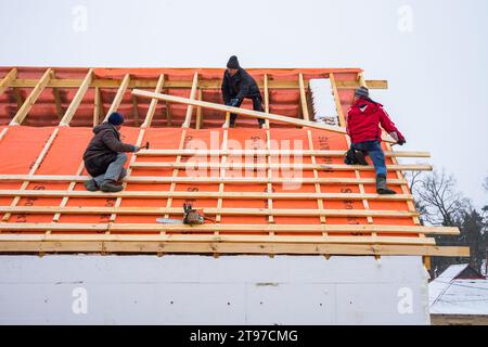 Irpin - Ucrania, marzo - 13, 2021: Contratistas de techado que instalan tablas de techo y barreras de vapor para baldosas de metal en invierno. Foto de stock