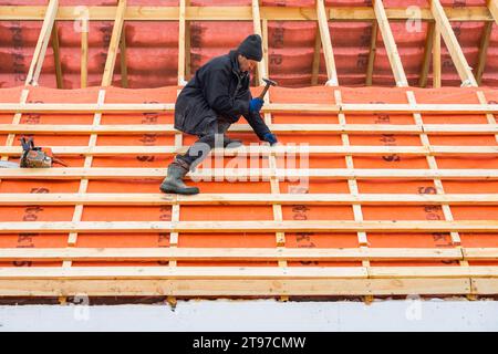 Irpin - Ucrania, Marzo - 13, 2021: Contratista de techos instalando tableros de techo y barreras de vapor en invierno. Foto de stock