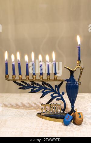 Menorah con velas encendidas para el día de fiesta judío Hanukkah en la mesa en casa. Celebrando el festival de las luces de Janucá. Dreidel en el lado Foto de stock