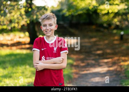 Un niño feliz en una camiseta de Liverpool en un parque Foto de stock