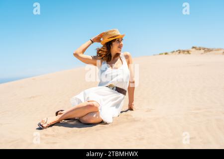 Mujer linda con sombrero sentado en la playa en Cabo de Gata, España Foto de stock