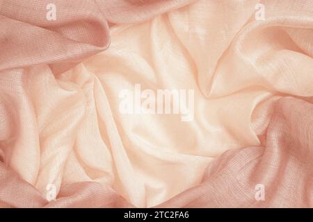 Tela de seda arrugada de cerca, color melocotón, textura suave, fondo textil pastel Foto de stock