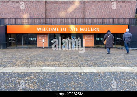 La gente entra y sale de la entrada de la sala de turbinas de la galería de arte moderno Tate en la orilla sur del río Támesis en Londres, Reino Unido Foto de stock