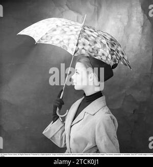mujer de los años 1950 con paraguas. Una mujer joven sostiene un paraguas. 1958. Kristoffersson ref DB73-7 Foto de stock