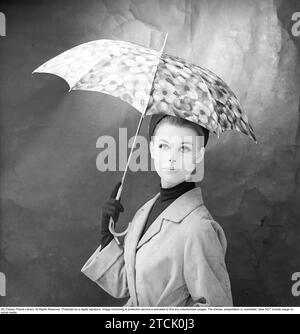 mujer de los años 1950 con paraguas. Una mujer joven sostiene un paraguas. 1958. Kristoffersson ref DB73-6 Foto de stock