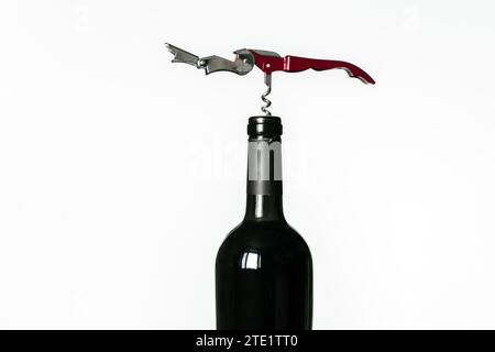 Sacacorchos atornillados en el corcho de una botella de vino tinto aislado sobre un fondo blanco Foto de stock