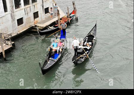 Gondoleros en góndolas tradicionales, visitas turísticas para turistas a través de canales estrechos, Venecia, Véneto, Italia Foto de stock