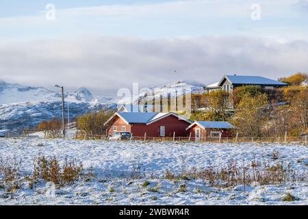 Casas inteligentes en la isla de Hillesøya, Noruega, con montañas nevadas en el fondo! casa de vacaciones, cabaña, albergue en invierno en un día soleado con nubes Foto de stock