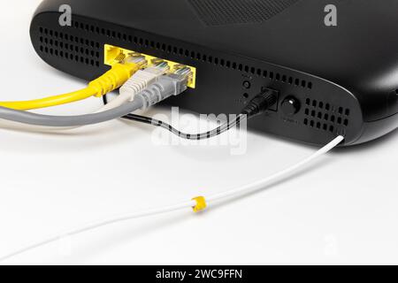 Terminal de abonado gpon negro con conexión a una red de Internet de fibra óptica y varios dispositivos con cables lan en una vista trasera de fondo blanco Foto de stock