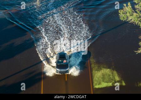 Carretera inundada en Florida después de fuertes lluvias de huracanes. Vista aérea de los coches de evacuación y rodeado de casas de agua en zona residencial suburbana Foto de stock