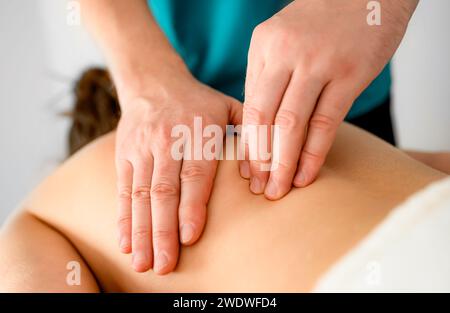 Terapeuta de masaje profesional haciendo masaje de puntos de activación en la espalda en el salón de masajes Foto de stock