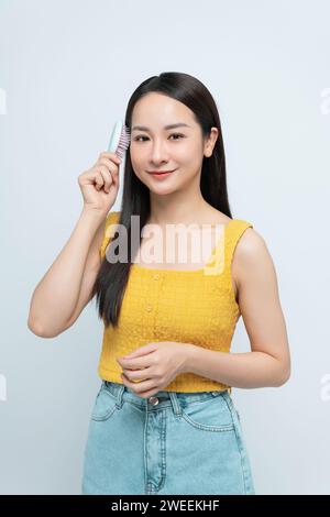 Retrato de mujer asiática sonriente cepillándose el pelo Foto de stock