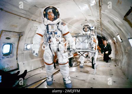 El astronauta Alan B. Shepard Jr., comandante del Apolo 14, tirando del transportador de equipos modulares bajo condiciones ingrávidas durante el ejercicio de entrenamiento a bordo de la Fuerza Aérea KC-135, con el astronauta Edgar D. Mitchell, piloto del módulo lunar, en el fondo, base de la Fuerza Aérea Patrick, Condado de Brevard, Florida, EE.UU., NASA, 4 de noviembre de 1970 Foto de stock