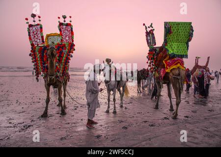 Gente local con camello y turistas en la playa de Clifton en Karachi, Pakistán. La línea costera del mar Arábigo. Foto de stock