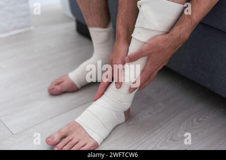 Hombre vendando el tobillo herido. Lesión en la pierna. Primeros auxilios para esguince de ligamento o tendón Foto de stock