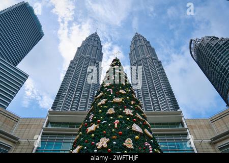 Kuala Lumpur, Malasia - 19 de diciembre de 2023: Árbol de Navidad gigante en el centro comercial Suria KLCC, con las Torres Gemelas Petronas en el fondo. Foto de stock