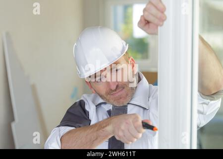 trabajador de la construcción instalando ventanas nuevas en la casa Foto de stock