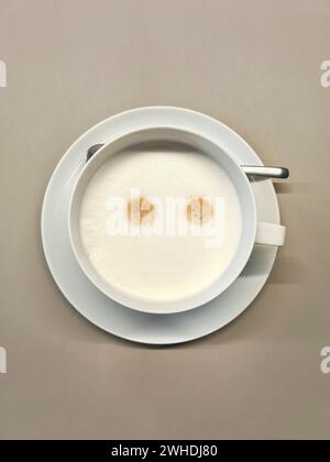 Latte elegantemente dispuesto en una taza blanca con espuma de leche Foto de stock