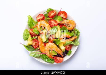 Ensalada saludable con camarones a la parrilla, aguacate, tomates cherry y hojas verdes en plato blanco aislado en fondo blanco top vi Foto de stock