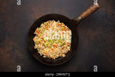 Auténtico arroz frito chino y asiático con huevo y verduras en wok vista superior, fondo de mesa de hormigón rústico. Di. Tradicional Foto de stock