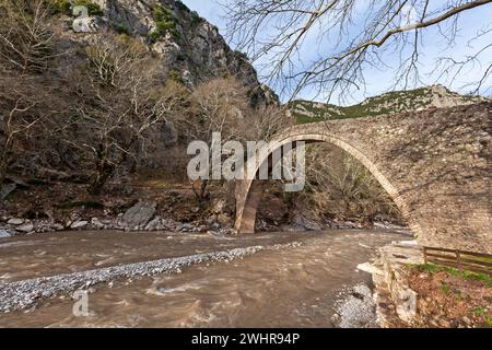 Puente de piedra sobre el río Portaikos, un viejo y hermoso puente construido en la forma tradicional de finales de los años 1800 y principios de los 1900 en el centro de Grecia, Europa. Foto de stock