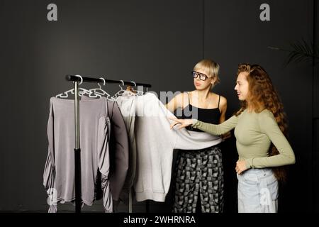 Estilista diseñador ayudando a elegir ropa de vestir al cliente. Foto de stock