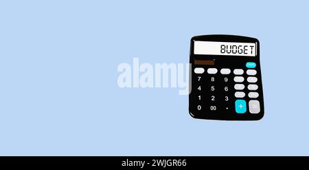 Calculadora con la palabra PRESUPUESTO en la pantalla y un fondo azul. Foto conceptual Foto de stock