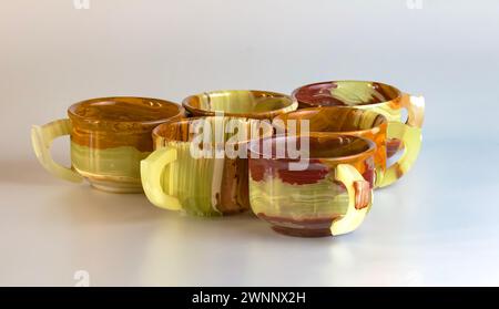 Vasos vacíos hechos de ónix multicolor en tonos amarillos-anaranjados sobre un fondo blanco. Foto de stock