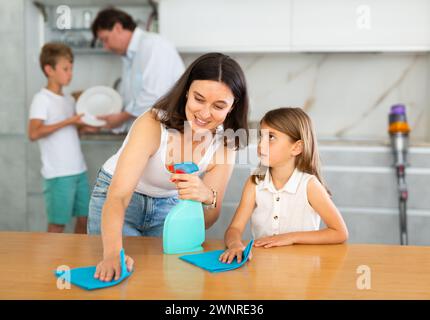 Familia feliz con dos niños haciendo limpieza en la cocina Foto de stock