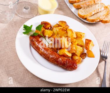 Las salchichas de butifarra fritas con rodajas de patata fritas se sirven en el plato Foto de stock