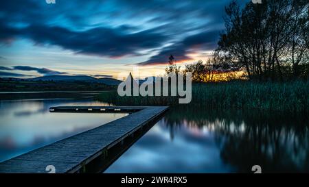 Un muelle de madera en el lago Llangorse, el Gower, Gales al atardecer Foto de stock