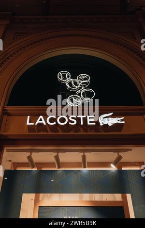 Fachada y logotipo de la tienda minorista de la marca Lacoste singboard en la tienda en el centro comercial Foto de stock