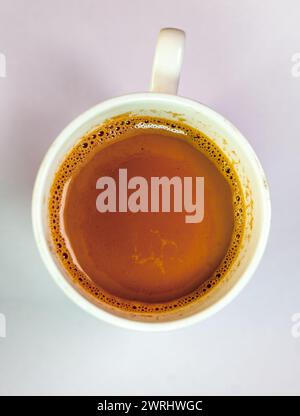 Una cautivadora fotografía de primer plano que muestra una taza de café caliente humeante en una clásica taza blanca Foto de stock