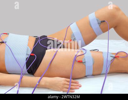 El procedimiento de mioestimulación en las piernas y glúteos de una mujer en un salón de belleza. Cuidar el cuerpo, reduciendo el exceso de peso. Foto de stock