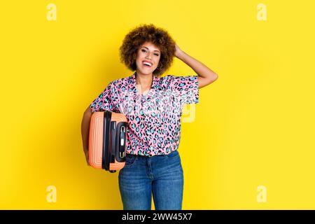 Foto de mujer positiva emocionada usa camisa de estampado animal con equipaje preparando vacaciones aisladas de fondo de color amarillo Foto de stock