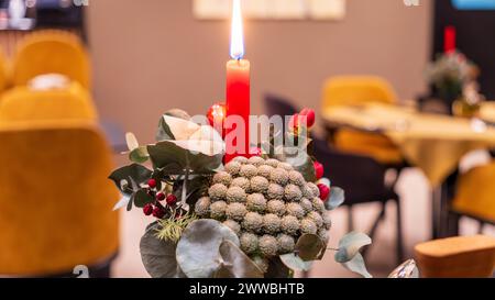 Una decoración de restaurante en una mesa con una vela roja encendida. Foto de stock
