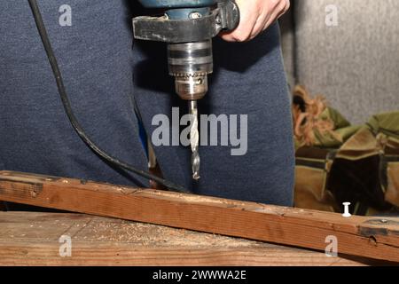 Hombre trabajador de madera usando la máquina de la prensa del taladro para hacer un agujero en las piezas de madera en el vicio. Foto de alta calidad Foto de stock