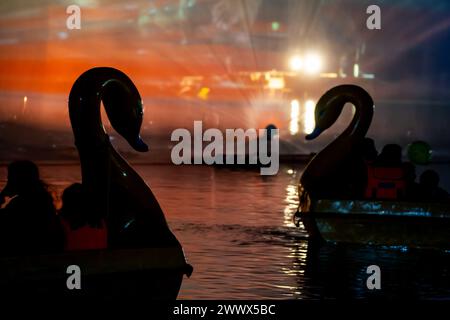 La gente en un barco en forma de cisne disfrutando de la luz, el sonido y las fuentes se muestran en el lago Gadisar que muestra el famoso lugar turístico cerca de Jodhpur y un lugar para Foto de stock