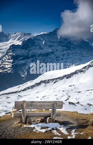 El primero, Suiza, un banquillo frente a una montaña de nieve Foto de stock
