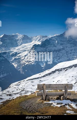 El primero, Suiza, un banquillo frente a una montaña de nieve Foto de stock