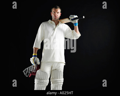 Jugador de cricket, de pie sosteniendo bate de críquet para llevar al hombro.