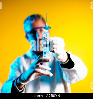Doctor con jeringa iluminada por la luz azul sobre fondo amarillo Foto de stock