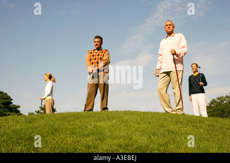 Ángulo de visión baja de dos hombres y dos mujeres de pie en un campo de golf