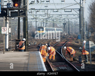 La línea principal de ferrocarril con los trabajadores de mantenimiento de alta visibilidad ropa de seguridad trabajando en la vía Foto de stock