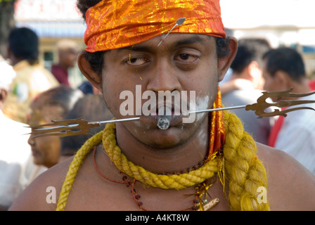Los indios malasios celebran el Thaipusam en Georgetown Penang. Un devoto fuma un queroot con la cara perforada Foto de stock