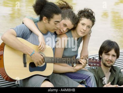 Cuatro jóvenes amigos reunidos alrededor de guitarra