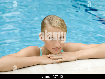 Mujer joven cabeza descansando sobre el borde de la piscina Foto de stock